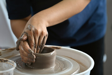 Fototapeta na wymiar The potter's hands working on the potter's wheel, making a cup from clay.