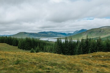 River surrounded by hills and grass on a cloudy day in Skye island, Scotland, UK