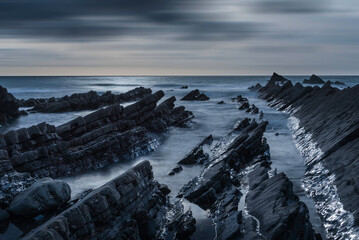 Beautiful sunset landscape image of Welcome Mouth Beach in Devon England with beautiful rock formations