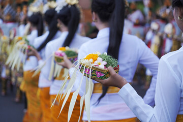 Group of women in traditional Balinese costumes carry religious offering for hindu ceremony on...