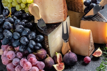 various types of cheese. with grapes and figs. composition with cheese knife. traditional pieces of Spanish, French, Italy cheese