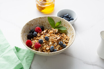 Grains granola with fresh berries in white bowl breakfast food concept blueberry honey