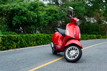 red classic italian scooter against the background of a green fence © Konstantin
