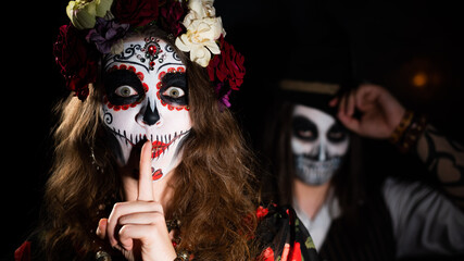 Woman in santa muerte costume and man in skeleton bodypainting for halloween.
