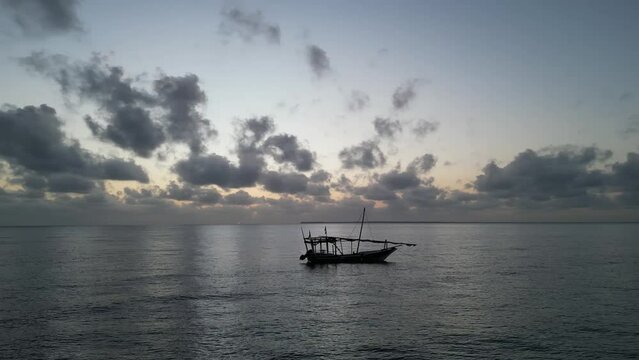 Fishing boat floating near Uroa beach coastline in Zanzibar Island, Tanzania Africa during sunset, Aerial orbit around shot