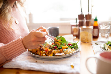 Close up shot of a woman eating a healthy vegetable dish and salad