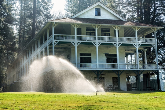  The historic Wawona Hotel, established in 1896 and a National Historic Landmark. A Victorian  lodge with wooden veranda and lawn sprinkler