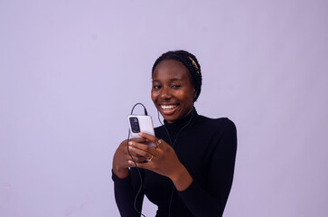 Excited african lady isolated over white background listening to music on her phone