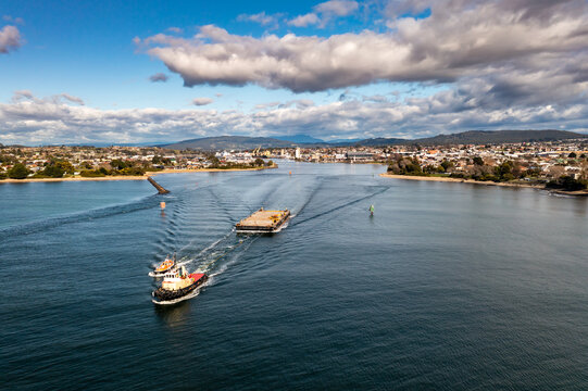 Tug boat towing salvage barge out to sea with pilot boat alongside