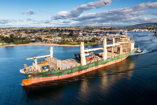Ship leaving port with scrapped tugboats on board