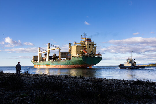 Ship leaving port with scrapped tug boats on board