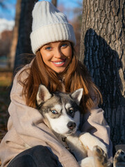 Young woman embracing her dog and looking at camera. Close-up vertical photo.
