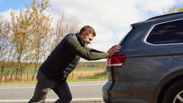 Man pushing a broken car down the road. Transportation, traveling concept