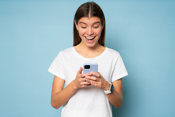 Excited woman using phone to shop online surprised with special offer on blue background