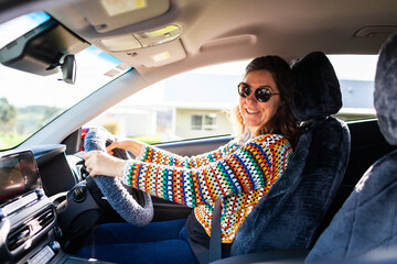 Portrait of happy middle aged woman driving electric vehicle car