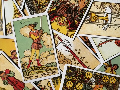 Picture of the Page of Swords tarot card from the original Rider Waite tarot deck with mixed tarot cards in the background