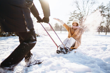 A man rolls a woman on a sled in the  winter snowy forest. Cold weather. Holidays, rest, travel concept.