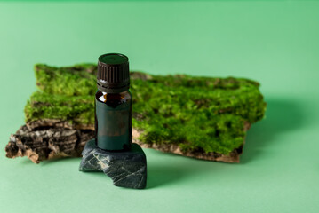 Composition With Bottle of Essential Oil on Tree Bark with Moss Beauty and SPA Concept Green Background Horizontal