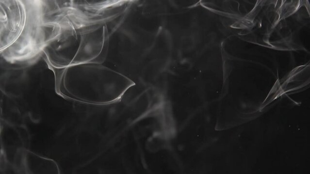 Time rewinds as smoke curls backwards against a black background.
