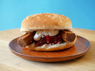 Sweet Burger on wooden background. Sweet unhealthy food concept. A Sugared burger with jam, cream, chocolate, burger bun