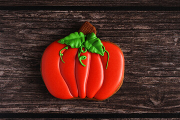 gingerbread in a glaze in the form of a pumpkin for Halloween on a wooden background close-up