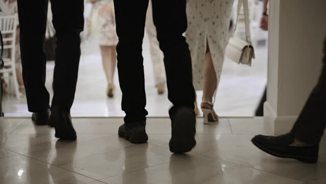Group of legs in elegant shoes descend stairs into banquet hall.