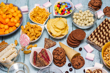 Salty and sweet snacks. Table of salty and sweet snacks. Large group of unhealthy food