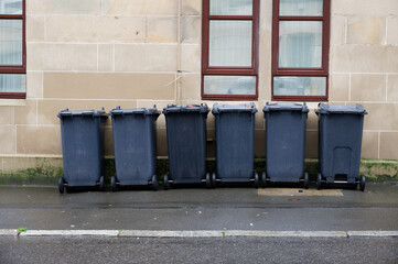 Wheelie bins in row for refuge collection outside council residential building