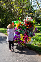 Woman in a hat with a bicycle and flowers in Vietnam