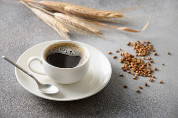 Gerstkoffie in witte kop, bonen en oren van gerst op grijze achtergrond. Beste natuurlijke cafeïnevrije biologische koffie-alternatief. Koffiesurrogaatdrank gemaakt van een gezonde melange van geroosterde gerst.
