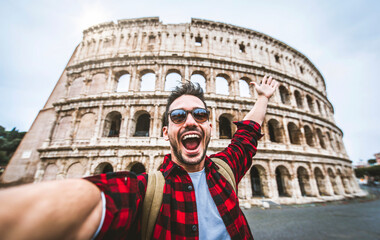 Happy tourist visiting Colosseum in Rome, Italy - Young man taking selfie in front of famous Italian landmark - Travel and holidays concept - obrazy, fototapety, plakaty