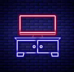 Glowing neon line TV table stand icon isolated on brick wall background. Colorful outline concept. Vector