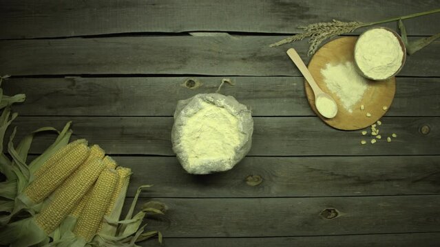 Corn and cornmeal on the table. Flat lay. Freshly harvested corncobs and cornmeal lie on an old wooden table. Camera movement over the table from right to left.