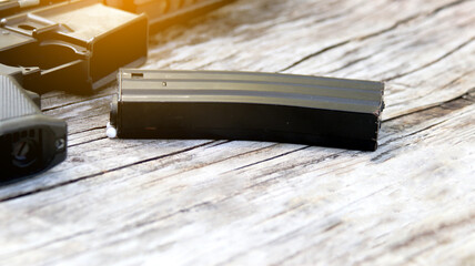 Close up magazine of air soft gun or bb gun on wooden floor, soft and selective focus on the magazine - obrazy, fototapety, plakaty