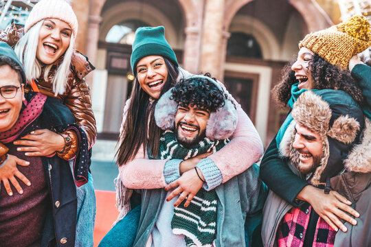 Happy group of friends wearing winter clothes having fun walking on city street - Young people laughing together hanging out on a sunny day - Friendship concept