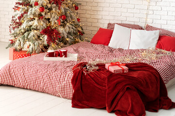 Winter Xmas Hygge home decor. Festive cozy bedroom in Skandinavian style with bed and two snow-covered decorated christmas tree with gifts. Concept new year and holidays. Interior design bedroom.	