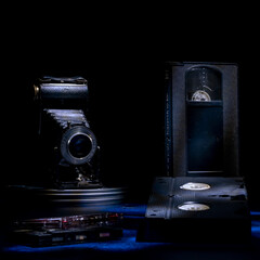 Composition of old vhs cassettes, cassette tapes and an antique bellows camera