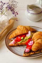 Breakfast with croissants. Two croissants with avocado, chocolate cream and balsam flowers....