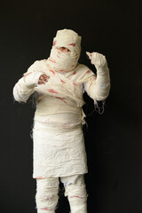Bandaged mummy in standing position with black background on Halloween day.