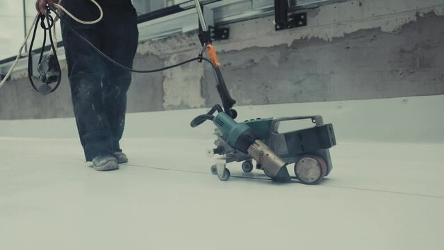 Roofer use welding machine for synthetic membrane on flat roof structure.