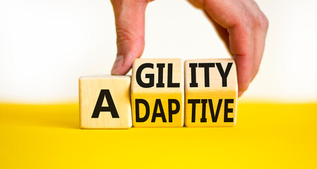 Agility and adaptive symbol. Concept words Agility and Adaptive on wooden cubes. Beautiful yellow table white background. Businessman hand. Business agility and adaptive concept. Copy space.
