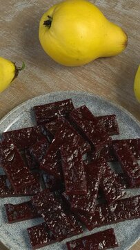 Membrillo - sweet, thick, sliceable firm paste made from quince fruit on a plate. Table spin. Vertical video. 