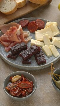 Plate with tapas: cheese, chorizo sausage, ham and membrillo sweet paste. Table spin. Vertical video.