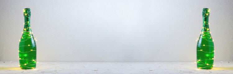 banner of a bottle of green champagne wrapped in a glowing garland like a Christmas tree. New year concept