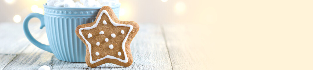 banner of a blue cup of winter hot drink with marshmallows and gingerbread star on a white wooden...