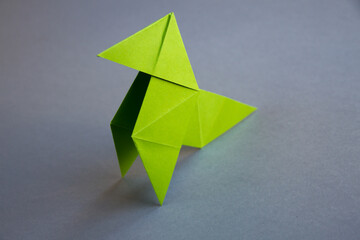 Green paper hen origami isolated on a grey background