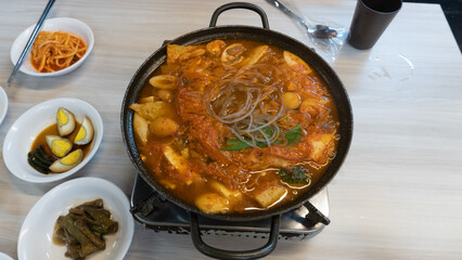 spicy kimchi stew or kimchi jjigae soup boiling on top of a table 