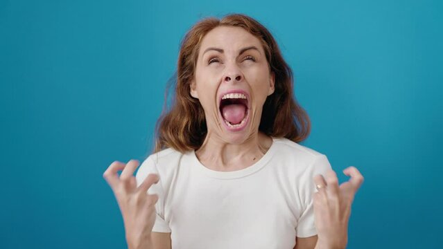 Young beautiful hispanic woman standing with furious expression over isolated blue background