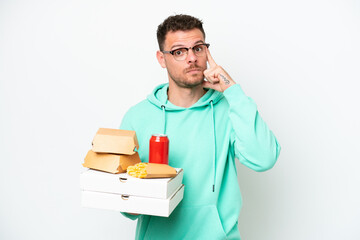 Young caucasian man holding fast food isolated on white background thinking an idea