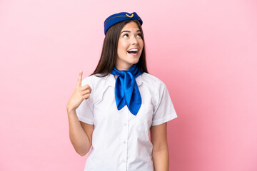 Airplane stewardess Brazilian woman isolated on pink background pointing up and surprised